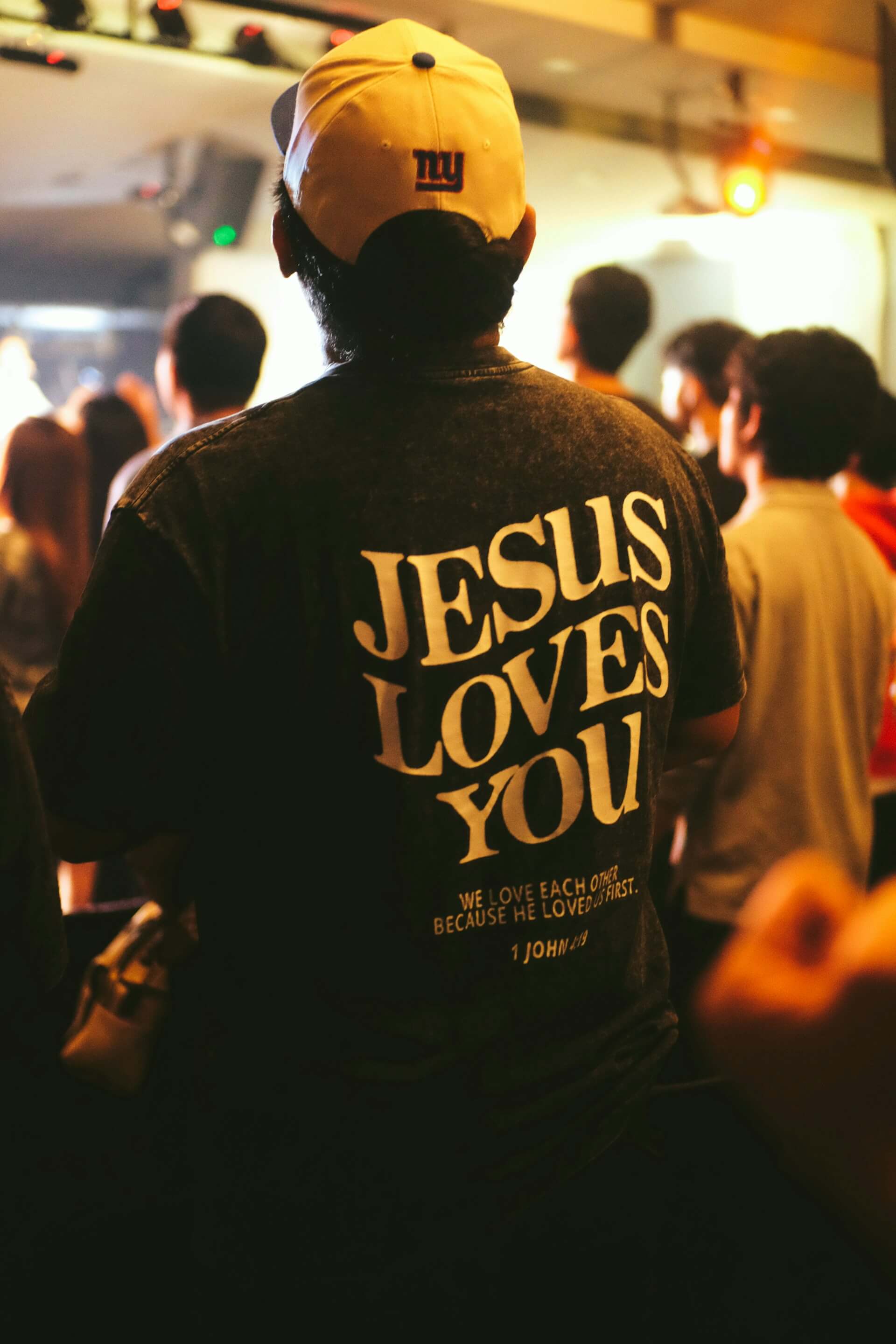 Person wearing a black Jesus Loves You message shirt at a church gathering