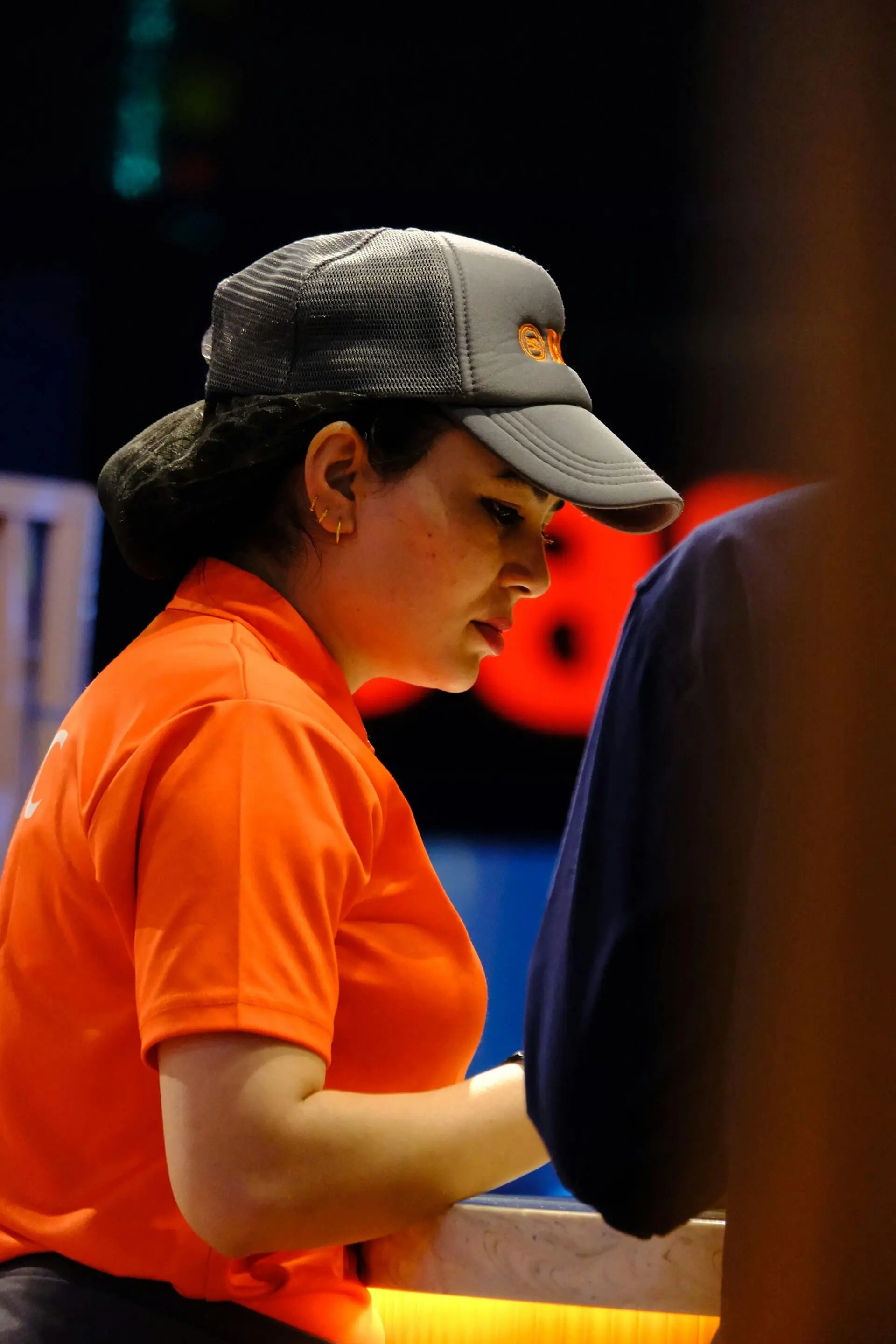 Employee wearing an orange polo and embroidered trucker hat